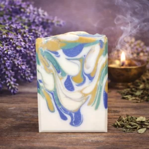 Handcrafted lavender patchouli goat milk soap with blue, green, and cream swirls on a soft botanical background