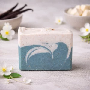 Single bar of Vanilla Jasmine goat milk soap with creamy white and sage green swirls, styled with jasmine flowers and vanilla beans