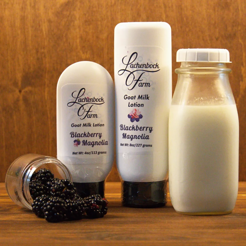 4 oz and 8 oz bottles of Blackberry Magnolia Goat Milk Lotion from Lachenbock Farm, shown with blackberries and a glass bottle of milk